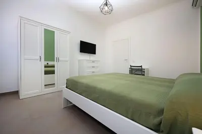 a white bedroom with a green bed and a television at Basilica San Paolo Nuvola EUR Modern apartment in Rome