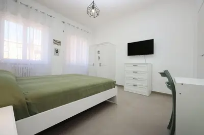 a white bedroom with a bed and a tv at Basilica San Paolo Nuvola EUR Modern apartment in Rome