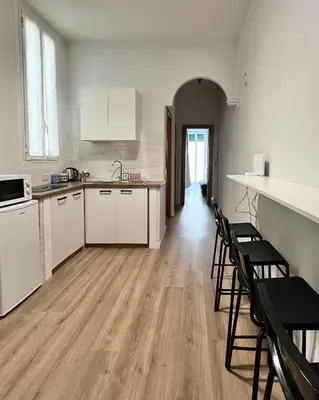 an empty kitchen with white cabinets and chairs at Lilia Charming Flat in Rome
