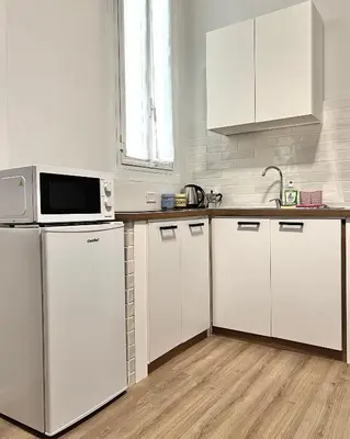 a white kitchen with white cabinets and a microwave at Lilia Charming Flat in Rome