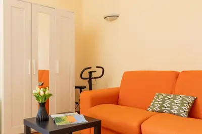a living room with an orange couch and a table at iFlat Bright & Comfy 2-Bedroom Apt near Vatican in Rome