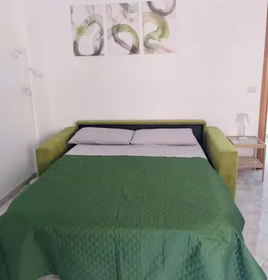 a bed with a green comforter in a room at Home Fermi 80 in Rome