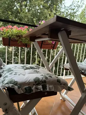 a wooden table with a bed on a balcony with flowers at Home Fermi 80 in Rome
