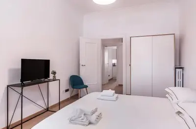 a white bedroom with a bed and a television at Pinturicchio's Key in Rome