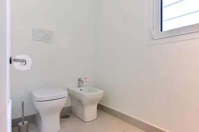 a white bathroom with a toilet and a window at Oasi Piceni Apartment San Lorenzo in Rome