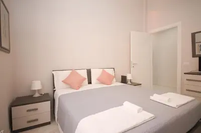a white bedroom with a large bed with pink pillows at Rome Flat 42 by GHOR in Rome