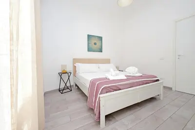 a white bedroom with a bed with a pink blanket at 4BNB - Cavalleggeri Apartment in Rome