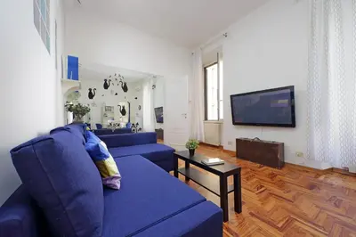 a living room with a blue couch and a tv at 4BNB - Lante Apartment in Rome