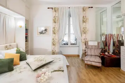 a bedroom with a bed and a chair and a window at Appartamento elegante Castel Sant'Angelo in Rome
