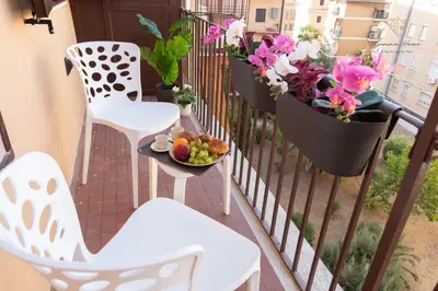a balcony with a table and chairs and flowers at Gemma House - 100mt to Metro Station, 2 En-Suite bathrooms in Rome