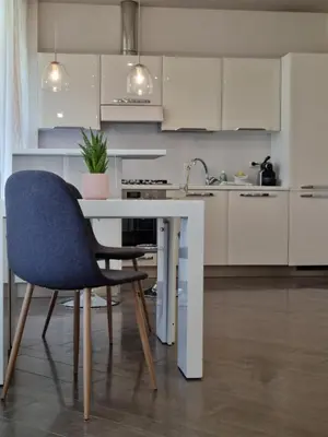 a white kitchen with a table and a blue chair at Relais Viola at the Vatican in Rome