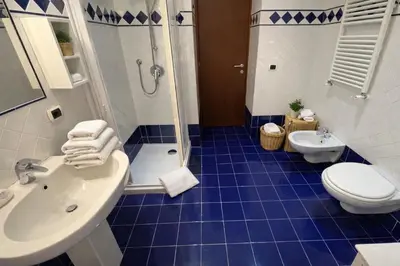 a blue tiled bathroom with a toilet and a sink at Apartment Cerri 2 in Rome