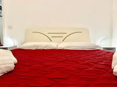 a bed with a red comforter and white pillows at Garbatella Vintage in Rome