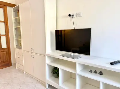 a living room with a tv on a white shelf at 10 minuti da stazione Trastevere in Rome