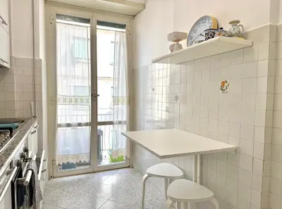 a white kitchen with a table and two stools at 10 minuti da stazione Trastevere in Rome