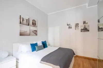 a white bedroom with a large bed with blue pillows at New apartment near Piazza del Popolo in Rome