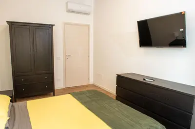 a bedroom with a bed and a dresser with a flat screen tv at Locazioni Ostiense - Joy House in Rome