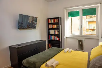 a bedroom with a yellow bed and a book shelf at Locazioni Ostiense - Joy House in Rome