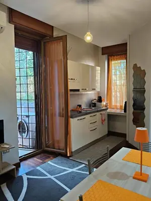 a kitchen with white cabinets and a table and a window at Roma Eur - OrangeVibes Loft in Rome