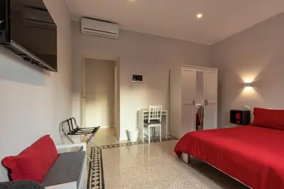 a bedroom with a red bed and a couch at CASA VACANZA San LO' ZONA SAN LORENZO TERMINI ROMA in Rome