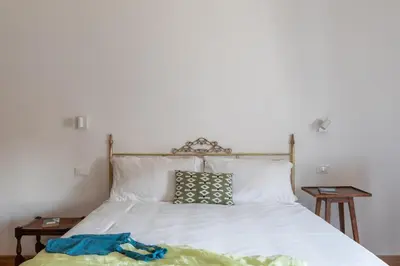 a bedroom with a bed with white sheets and two tables at iFlat Pantheon Peaceful & Comfortable Apartment in Rome