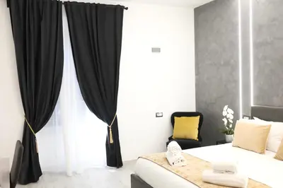 a bedroom with black curtains and a bed and a chair at Turati Inn in Rome