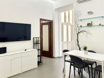 a white living room with a table and a tv at DaliTourism - Vatican Apartment 118 in Rome