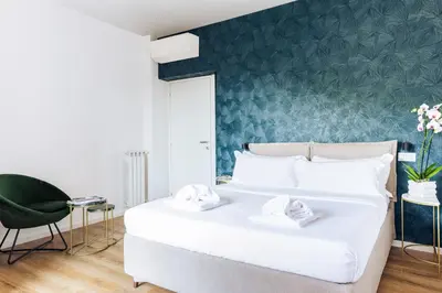 a bedroom with a white bed and a green wall at Elysium Suites Colosseo in Rome