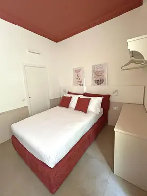 a bedroom with a white bed with red and white pillows at Astom Suites in Rome