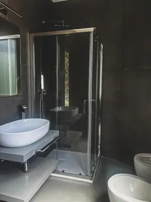 a bathroom with a glass shower and a sink at J Maluni City Hotel in Rome