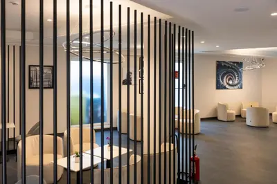 a room with a partition with white chairs and a room withazesktop at J Maluni City Hotel in Rome