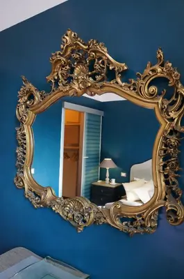a gold mirror on a blue wall in a bedroom at A Casa Di Elle in Rome