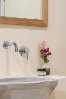 a sink with a mirror and a vase of purple flowers at Reginella Luxury Apartment in Rome
