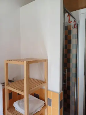 a bathroom with a wooden shelf in a shower at Greta's house in Rome
