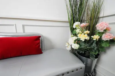 a red pillow sitting next to a vase of flowers at Suite Spagna 29 in Rome