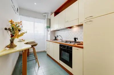 a kitchen with white cabinets and a table with a vase of flowers at Gaia's Place! in Rome
