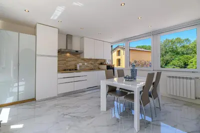 a kitchen with white cabinets and a white table and chairs at Appia Antica Park - Apartment with Terrace in Rome