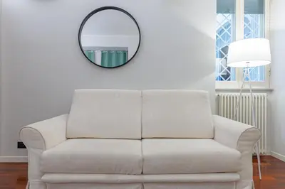 a white couch in a living room with a mirror at Vicomoro House Trastevere in Rome
