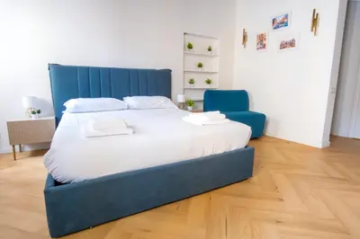 a large bed in a room with a blue chair at Elegantis Trevi Suite Apartment - Just 50m from Trevi Fountain in Rome