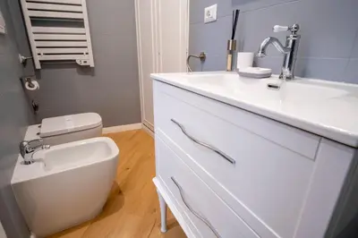 a white bathroom with a sink and a toilet at Elegantis Trevi Suite Apartment - Just 50m from Trevi Fountain in Rome