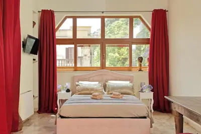 a bedroom with a bed with red curtains and a window at Luxury Trastevere Terraces in Rome