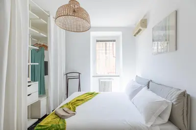 a white bedroom with a bed with a green blanket on it at iFlat Colosseum Modern & Peaceful Design Apt in Rome
