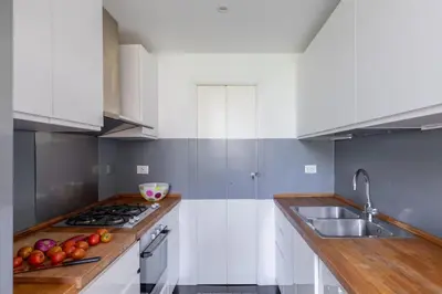 a kitchen with white cabinets and a sink at iFlat Colosseum Modern & Peaceful Design Apt in Rome