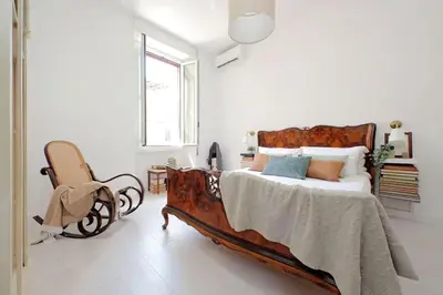 a bedroom with a large bed and a chair at Eroi Spacious Apartment in Rome