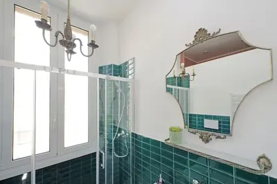 a bathroom with green tiles and a mirror at Eroi Spacious Apartment in Rome
