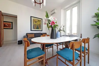 a dining room with a table and chairs with a vase of flowers at Eroi Spacious Apartment in Rome