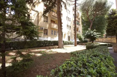 a building with a tree and bushes in a park at Garbatella 2BR Holiday House in Rome