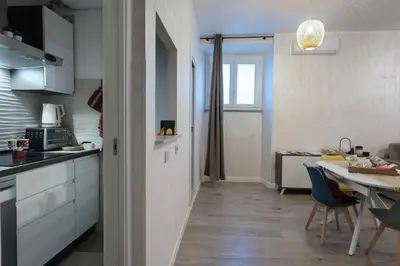 a kitchen with white cabinets and a table with chairs at 2passi dal Colosseo in Rome
