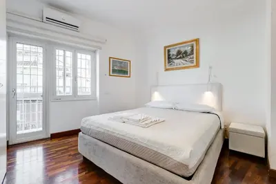 a white bedroom with a bed and two windows at HYRIA Holiday Home in Rome