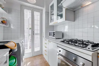 a white kitchen with a stove and a sink at HYRIA Holiday Home in Rome